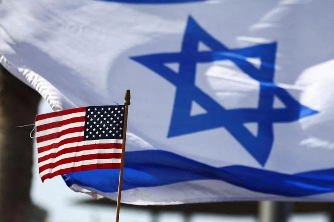 FILE PHOTO: A view of a U.S. flag and an Israeli flag held up by people during a demonstration to show support for U.S. President Joe Biden, for not inviting Israeli Prime Minister Benjamin Netanyahu to the White House, in front of the U.S. Consulate in Tel Aviv, Israel, March 30, 2023. REUTERS/Ronen Zvulun/File Photo