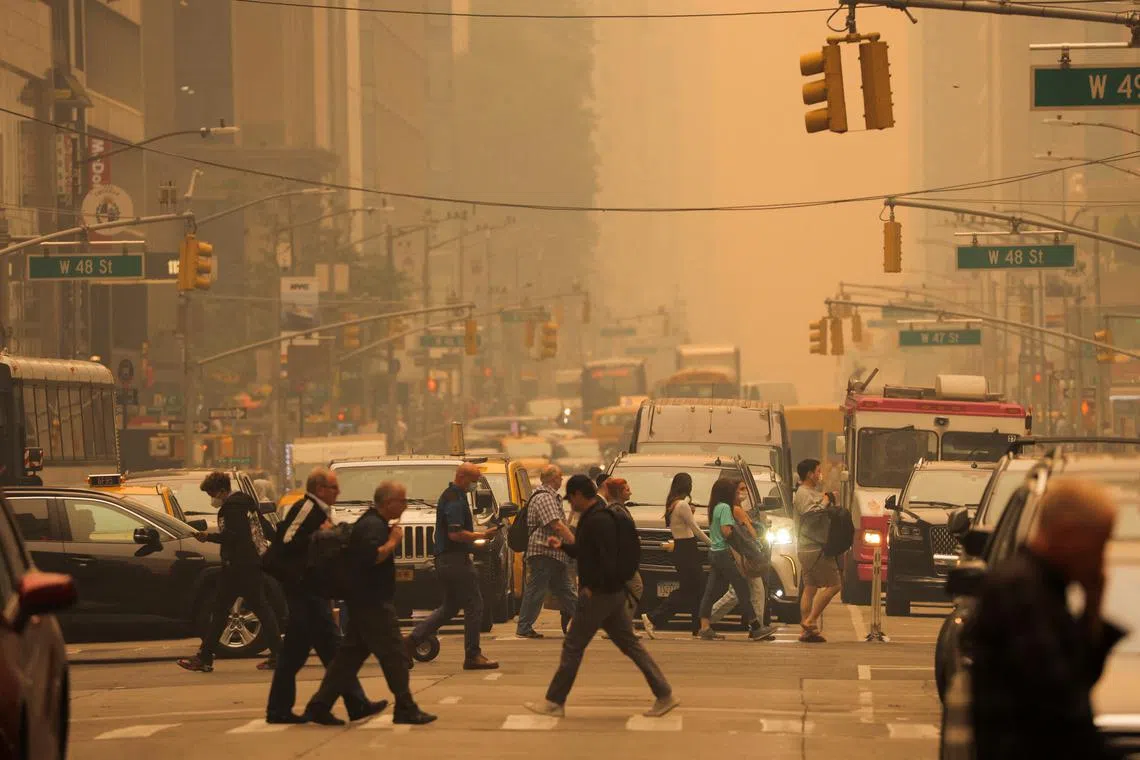 People walk at 6th Avenue as haze and smoke caused by wildfires in Canada blanket New York City on June 7, 2023. 