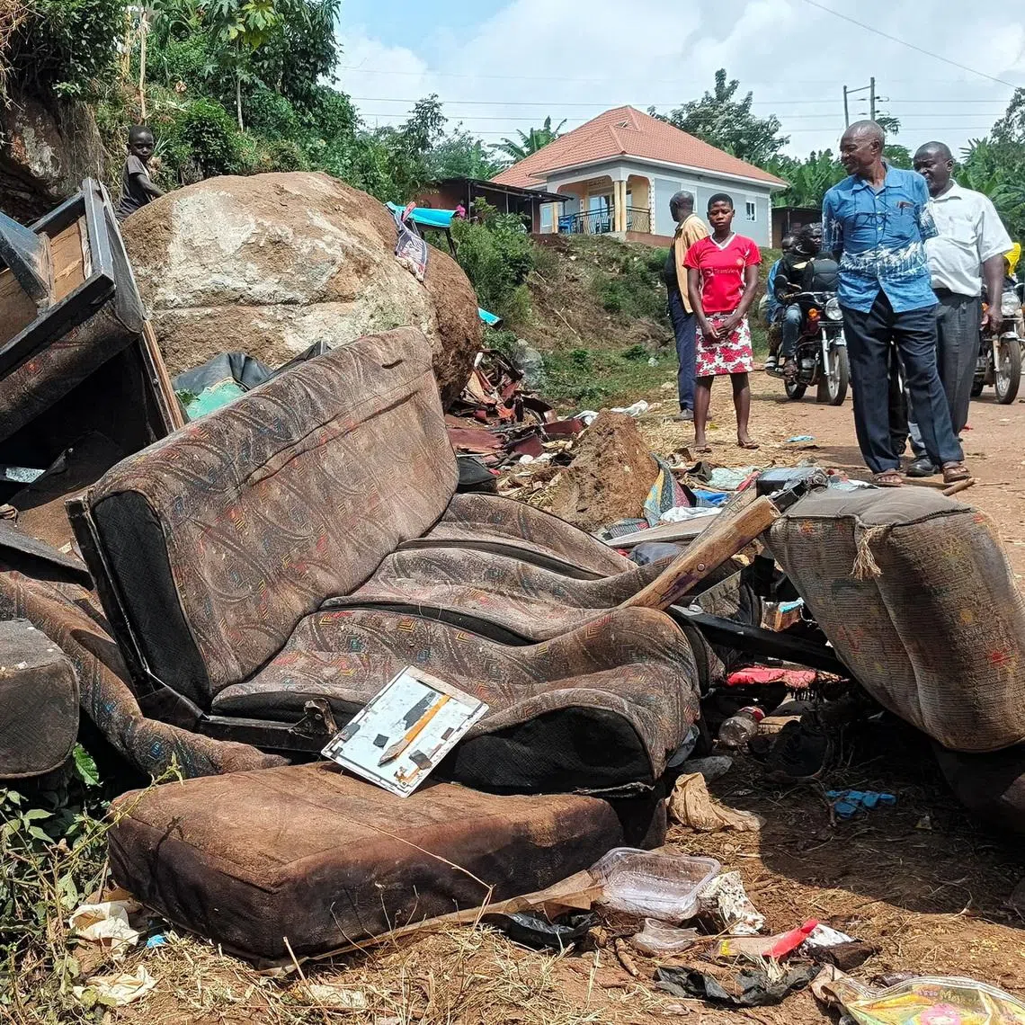 People walk near the wreckage of a bus, owned by King David Junior School, on the shoulder of the road following an accident that killed schoolchildren on the way back from an educational visit to Sipi Falls, at Chekwatit village in Kapchorwa district, Uganda, July 17, 2026. Picture taken with a mobile phone. REUTERS/Stringer
