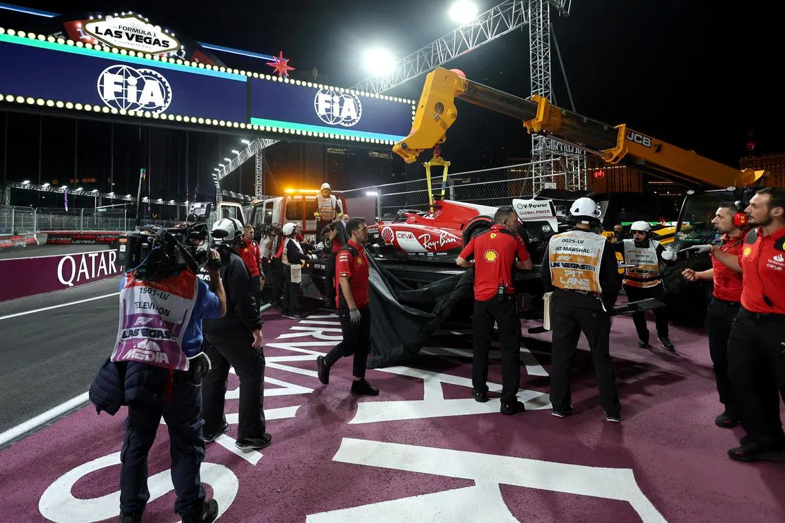 Stewards using a crane to remove the Ferrari of Carlos Sainz Jr after the cancellation of the first practice session due to a drain cover that came off the asphalt and hit the car.  