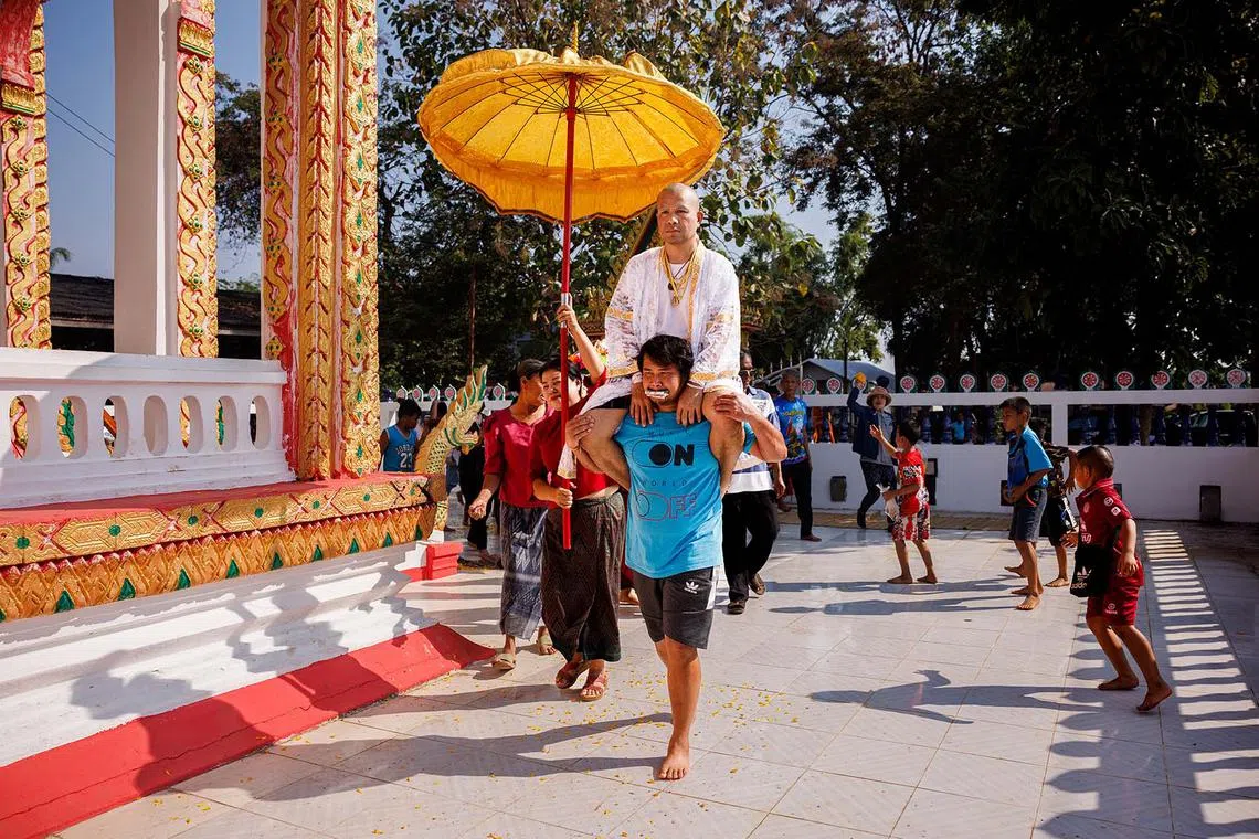Former hostage, Bunthom Phankong, is carried into the temple by his nephew, Samakr Phankong, before his ordination ceremony at Wat Samakkhi Phatthanaram in Udon Thani, Thailand on Dec. 11, 2023. 