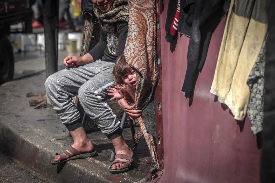 A Palestinian child stands at a tent for displaced people in a main street in Rafah, in the southern Gaza Strip, on Feb 19, 2024.