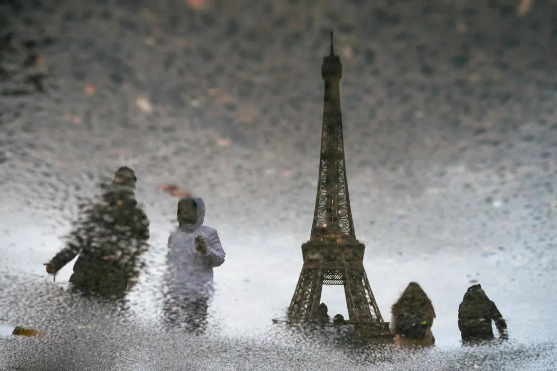 A reflection of tourists walking past the Eiffel Tower in Paris, on Jan 26, 2025.