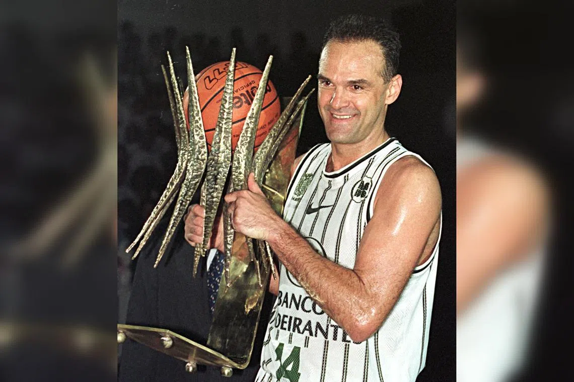 Brazilian basketball star Oscar Schmidt holding a trophy in 1998 marking his 22 years of professional play.