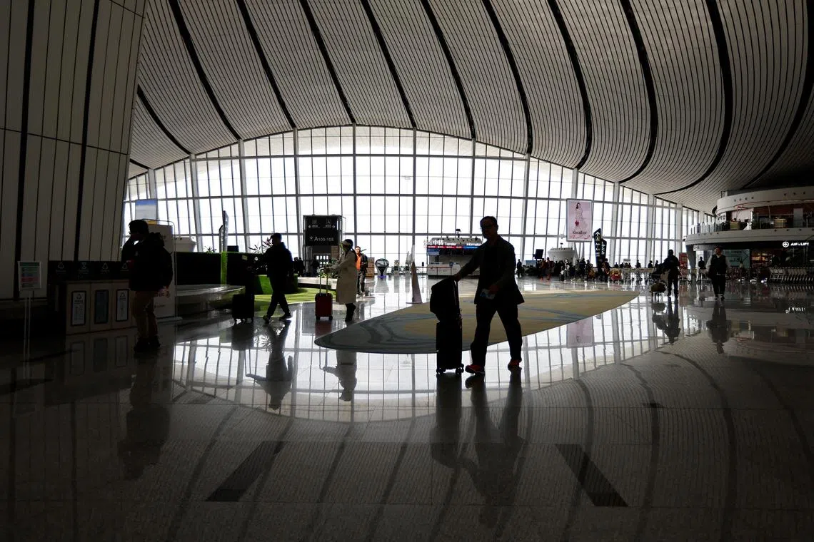 FILE PHOTO: Travellers walk with their suitcases at Beijing Daxing International Airport in Beijing, China April 24, 2023. REUTERS/Tingshu Wang/File Photo