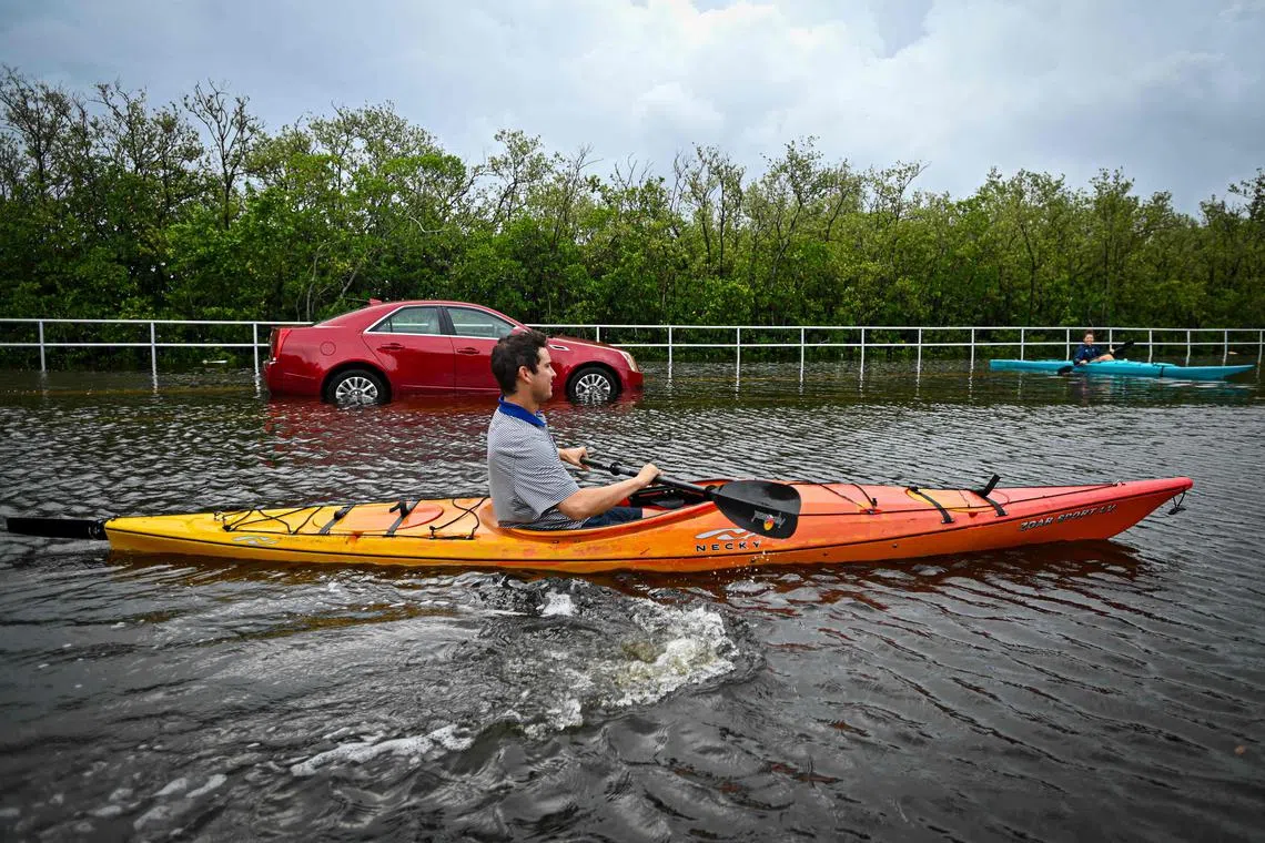 Residents use kayaks to travel on a flooded road in Tampa, Florida.