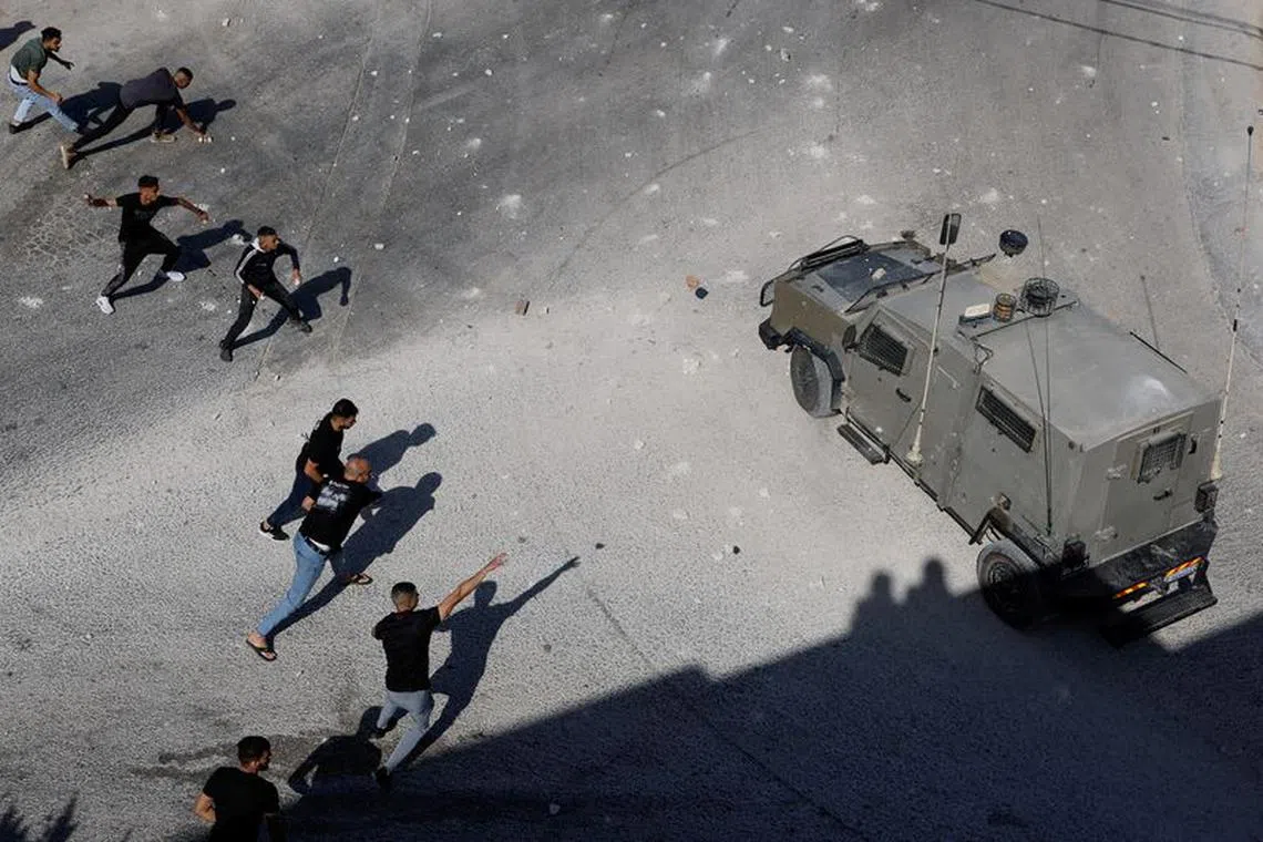 Palestinians throw objects next to an Israeli military vehicle during a raid near Tubas in the Israeli-occupied West Bank, September 1, 2023. REUTERS/Raneen Sawafta