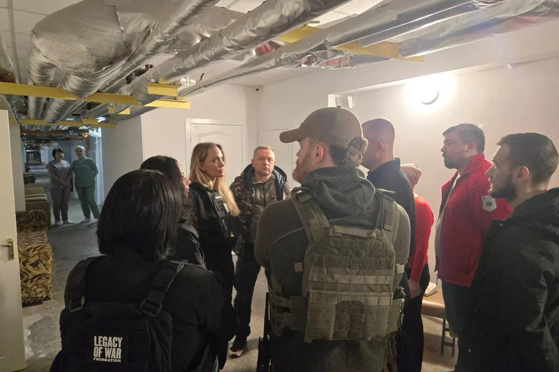 Angelina Jolie and others stand indoors with flak jackets on, in Kherson, Ukraine, in this handout image released on November 6, 2025. Legacy of War Foundation/Handout via REUTERS