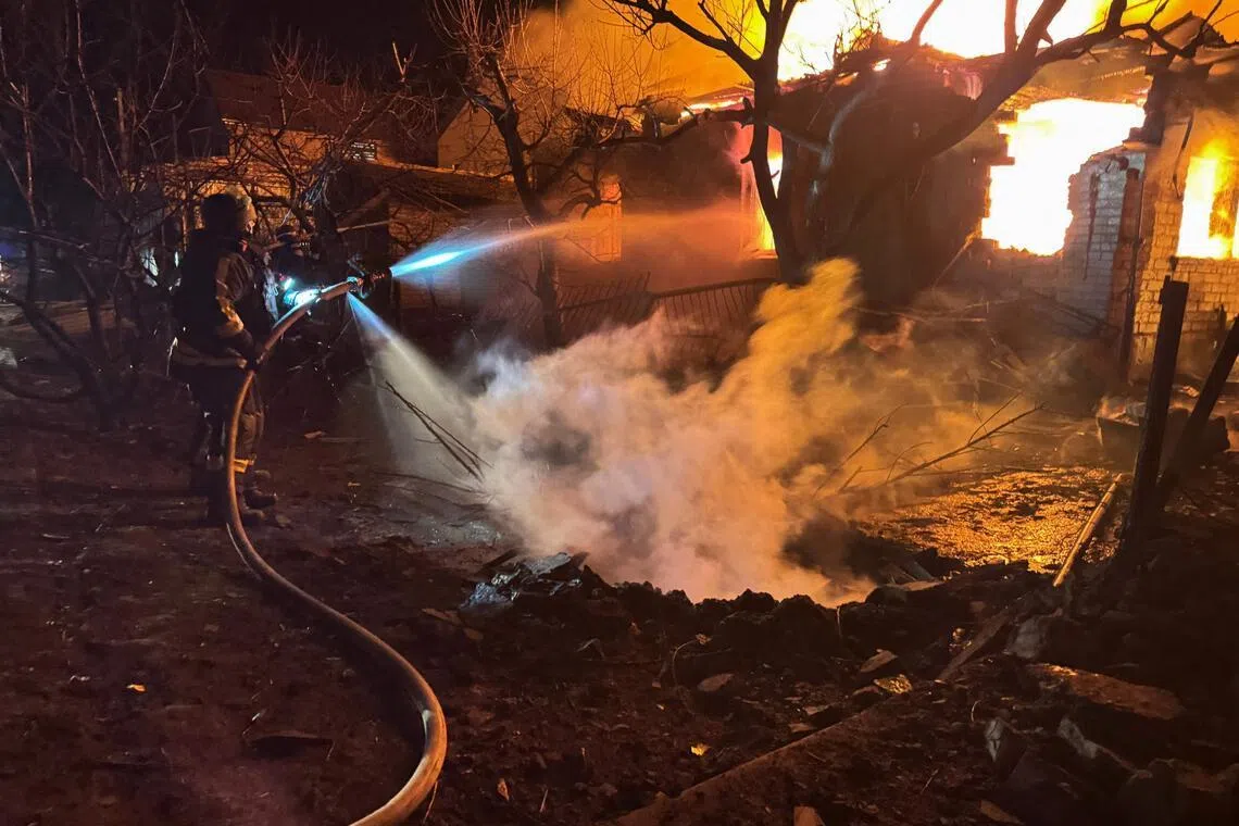Firefighters extinguish a fire in a residential house following a drone strike in Zaporizhzhia early on March 16, amid the Russian invasion of Ukraine.