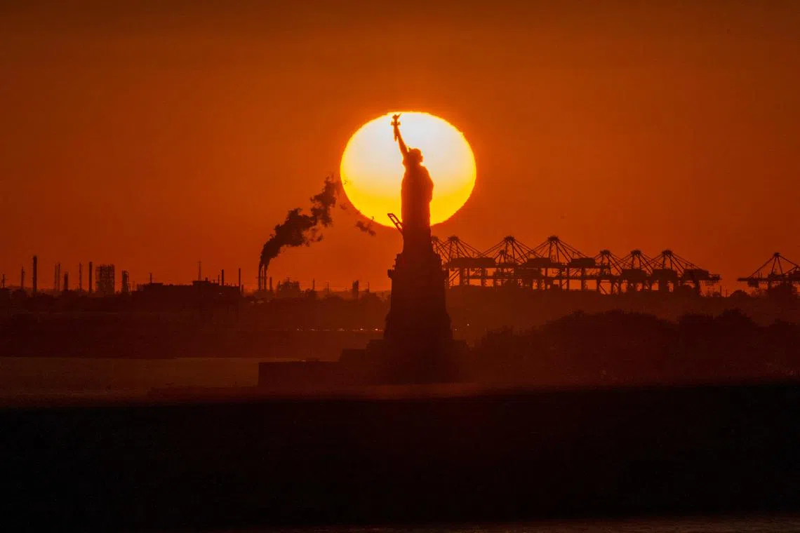 The sun sets behind the Statue of Liberty in New York on November 3, 2022.
