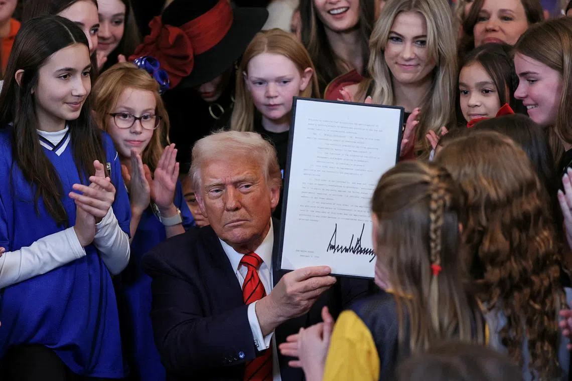 US President Donald Trump holds up a signed executive order banning transgender girls and women from participating in women's sports.
