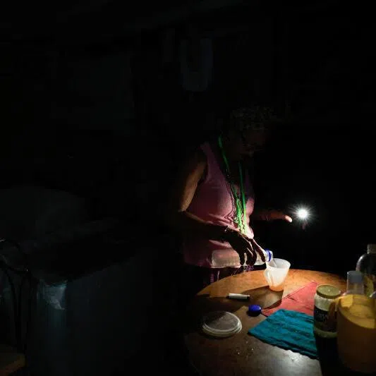 Retired nursing assistant Ana Amelia Gracias, 70, pours herself water at home as Cuba’s national electric grid collapsed at midday on July 6, in Havana, Cuba.