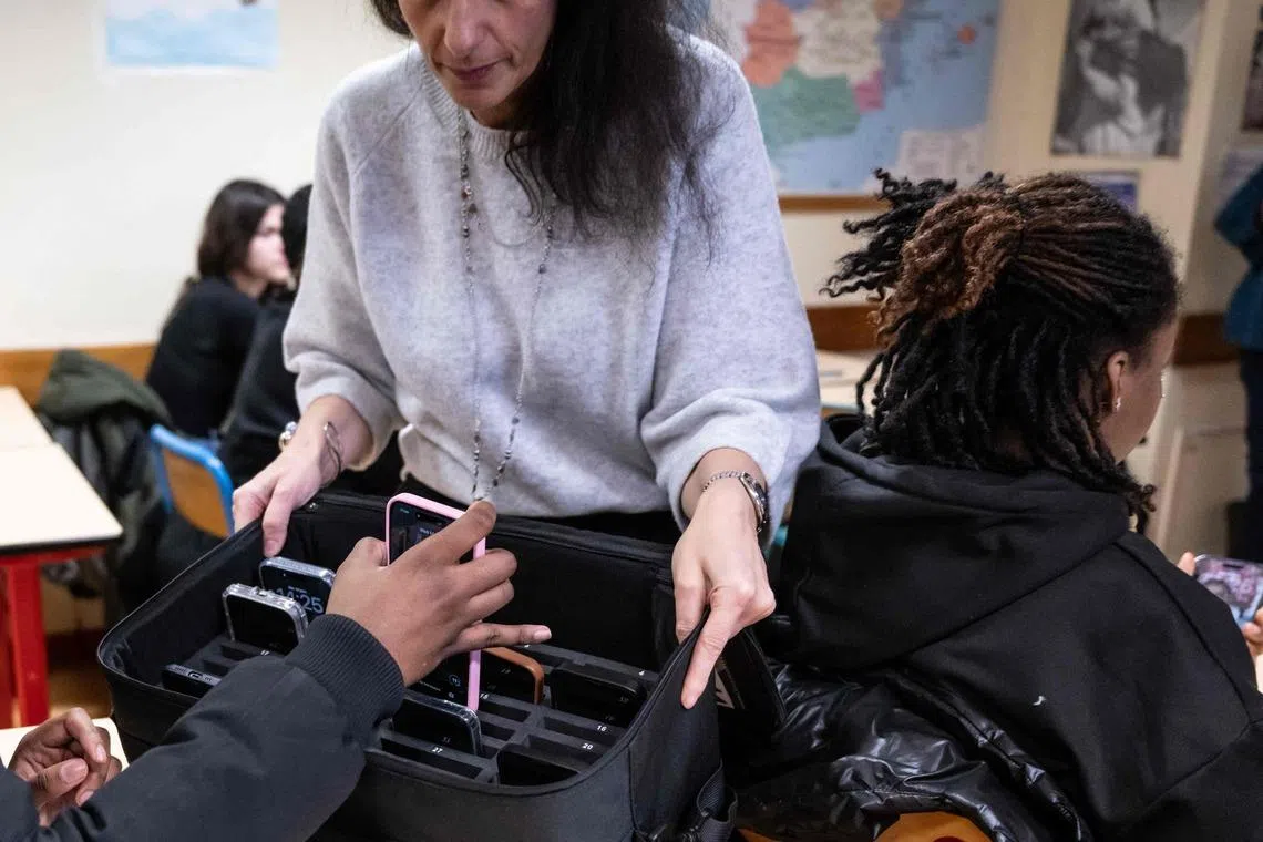 A teacher collects a student's mobile phone at the Jean Mermoz vocational high school in Montsoult, Paris, on Jan 14.