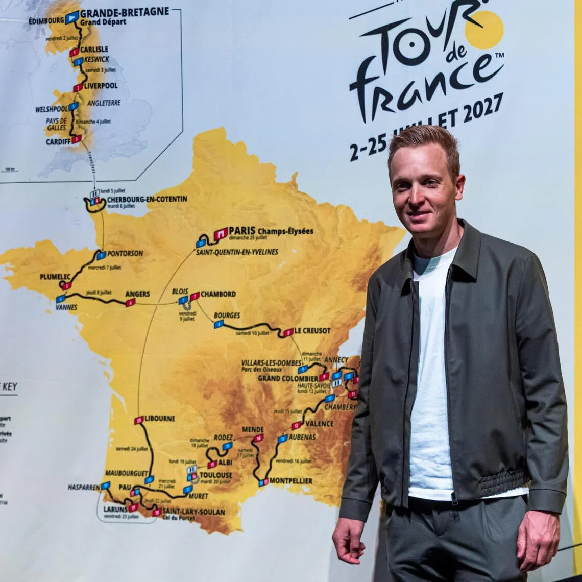 Belgian cyclist Tim Merlier posing for photographs in Paris on Oct 22, next to a map of the stages for the 2027 Tour de France cycling race.