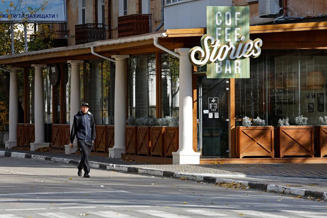 A man walks past a closed bar in Kherson on Oct 31, 2022.