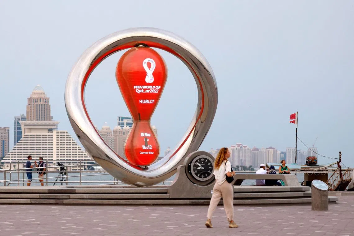 A picture taken on Nov 15, 2023 shows people walking past the 2022 World Cup countdown clock at the Corniche promenade in Doha. 