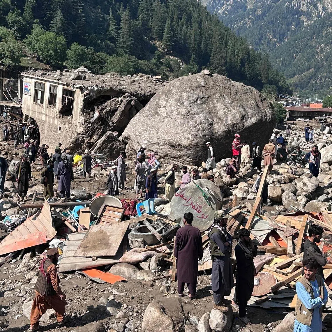 Afghan men stand amidst destroyed shops after flash floods hit Parun town in Afghanistan’s Nuristan province.