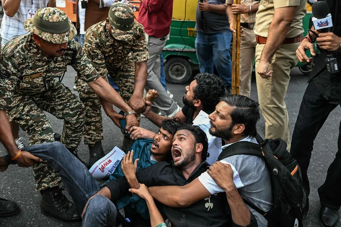 Security personnel detaining demonstrators during a protest in New Delhi on Oct 11.
