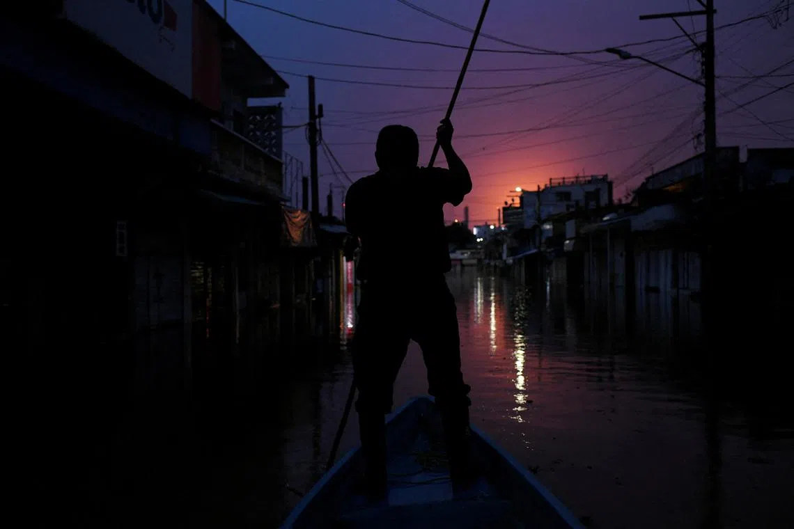 A man navigating his a boat along a flooded street due to the overflowing of the Tesechoacan river after heavy rains, in Jose Azueta, Mexico, on Oct 27, 2024. 