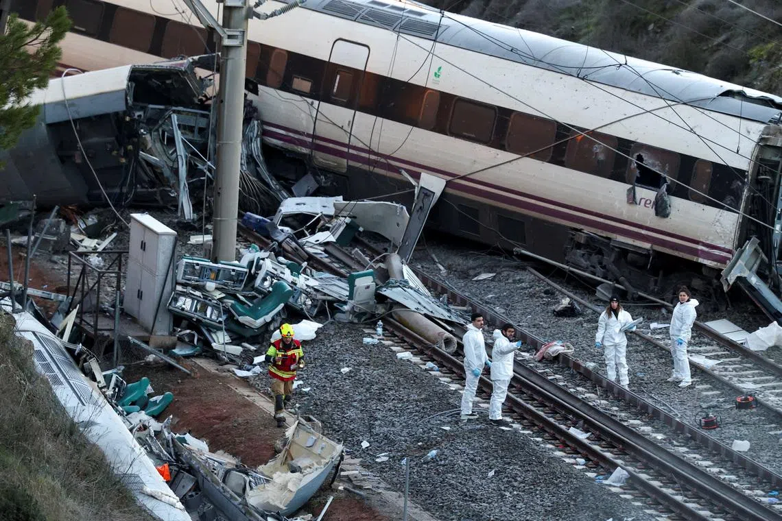 A firefighter and members of the Spanish Civil Guard work next to one of the trains involved in the accident, at the site of a deadly derailment of two high-speed trains near Adamuz, in Cordoba, Spain, January 19, 2026. REUTERS/Susana Vera