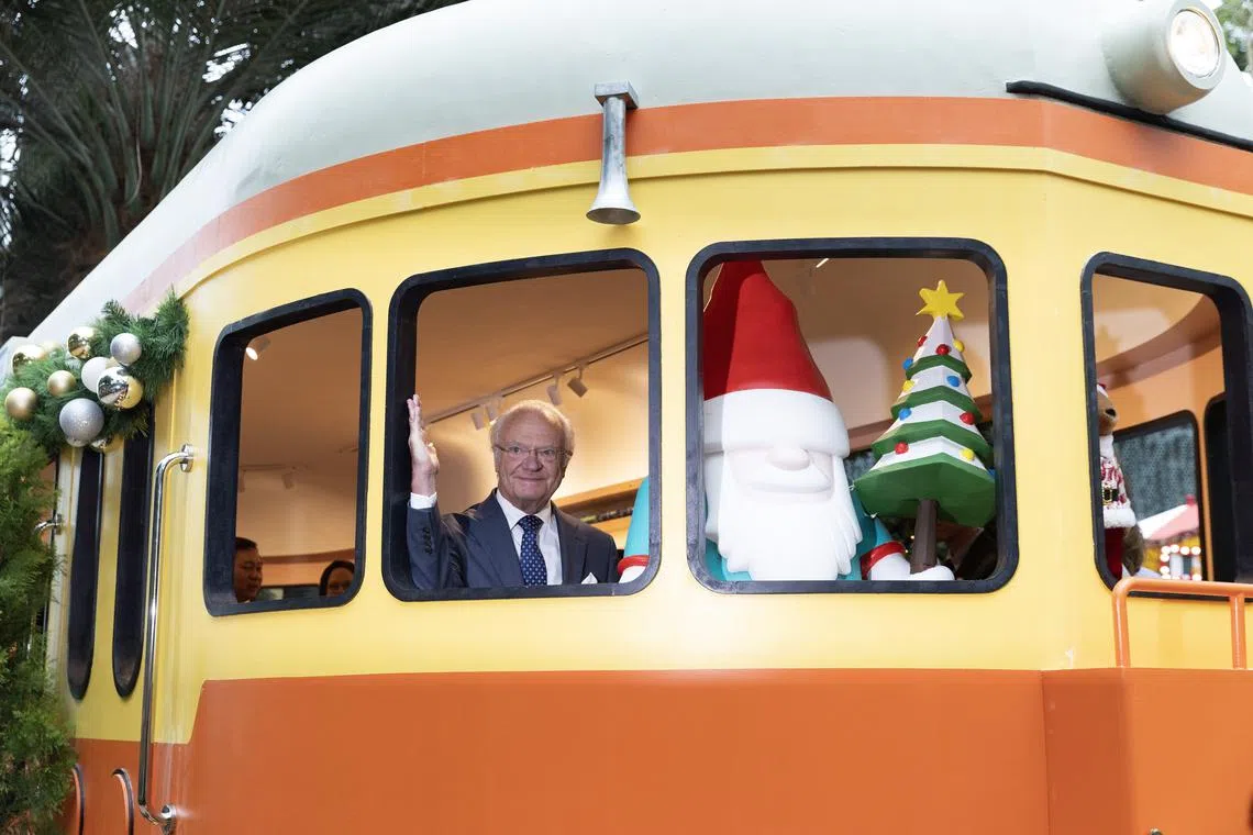 Sweden’s King Carl XVI Gustaf poses for a photo in a model train as he tours the Christmas Train Show at Gardens by the Bay.