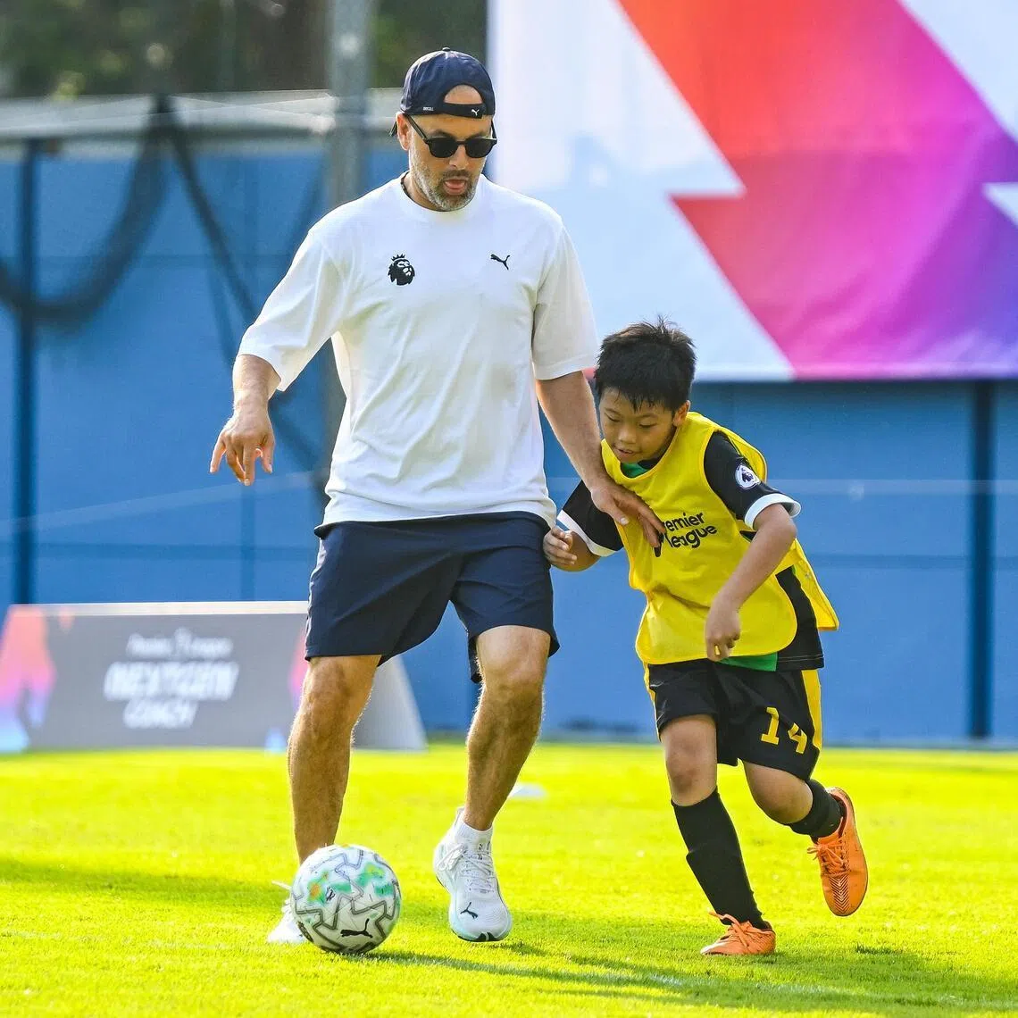 Former Chelsea and Liverpool player Joe Cole and a young player in a match during the Premier League NEXTGEN Coach Football Festival at the Jalan Besar Stadium on May 23.