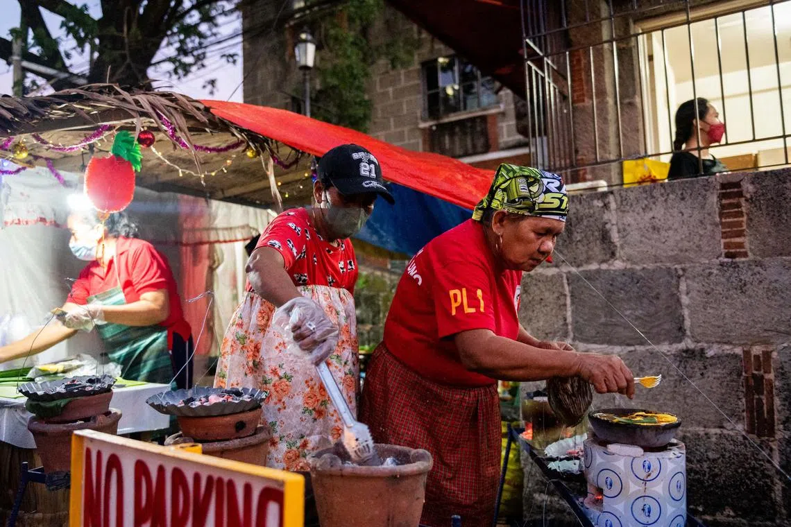Women cook bibingka, a Filipino rice cake, during the first of the nine-day dawn mass known as Misa de Gallo, ahead of Christmas, at the Saint Joseph Parish, in Las Pinas City, Metro Manila, Philippines, December 16, 2022. REUTERS/Lisa Marie David