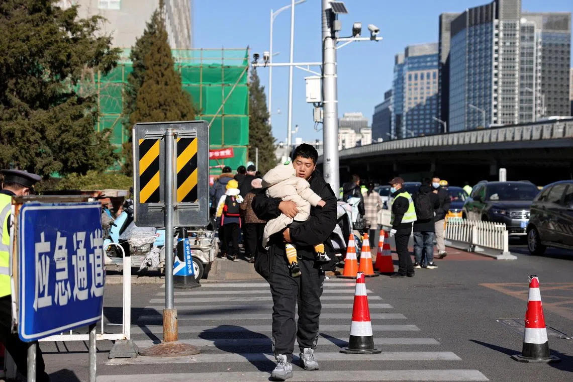 A man carries a child outside a children's hospital in Beijing, China November 24, 2023. REUTERS/Florence Lo