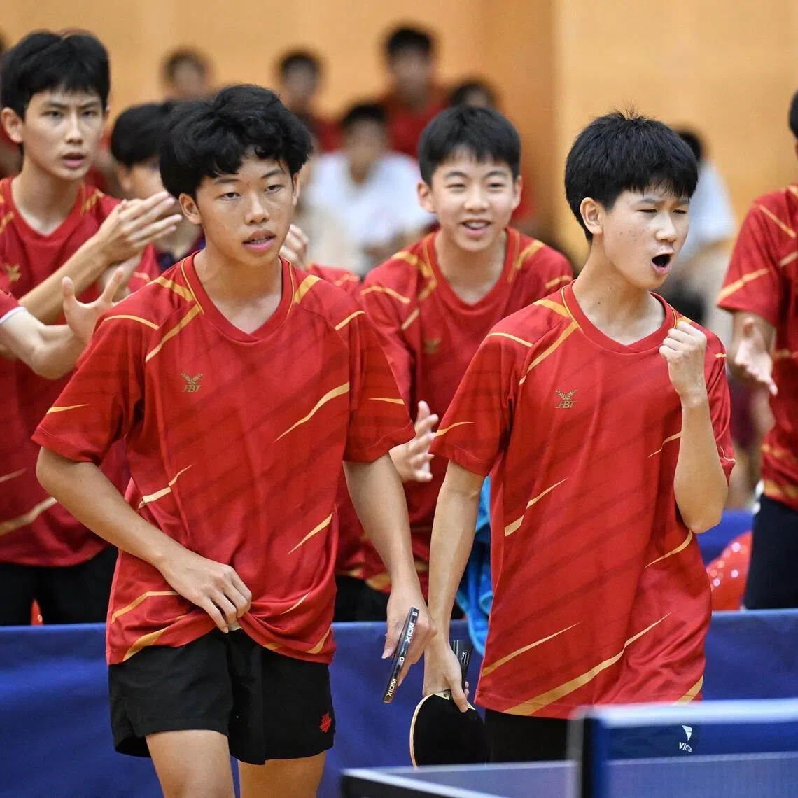 Hwa Chong Institution paddlers Rayner Young (left) and John Ang are cheered on by their team mates during their match against Raffles Institution in the B Division Boys table tennis final on April 9.