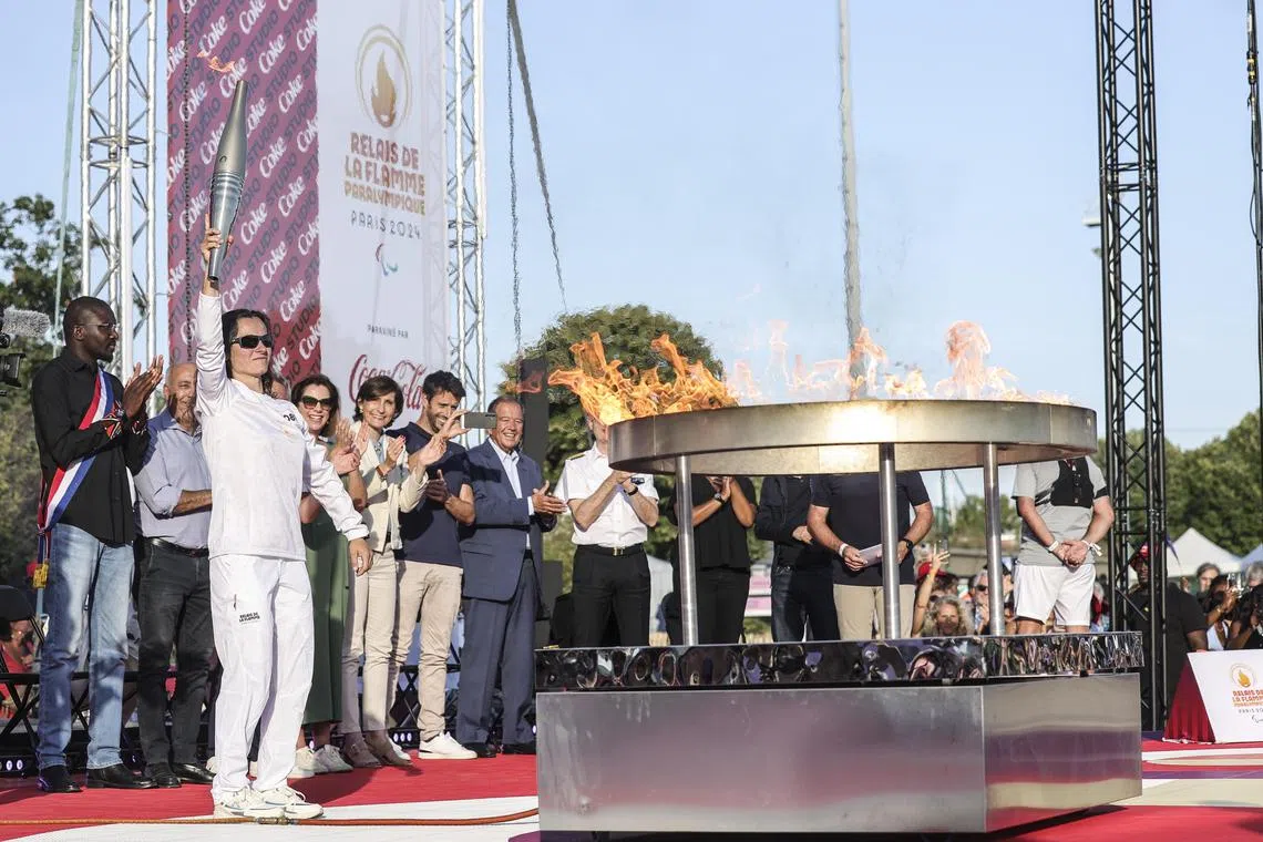 French para judoka Sandrine Martinet (left), a 2016 gold medallist, lighting the Paralympic cauldron in the suburbs of Paris, on Aug 27.