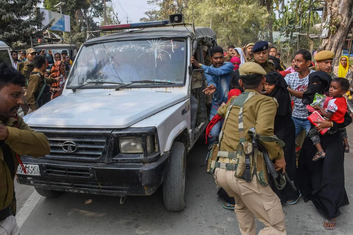Police personnel take arrested people allegedly involved in child marriages to present before a court in a vehicle as their relatives react, near Mayong police station in Morigaon district of Assam on February 4, 2023. (Photo by Biju BORO / AFP)