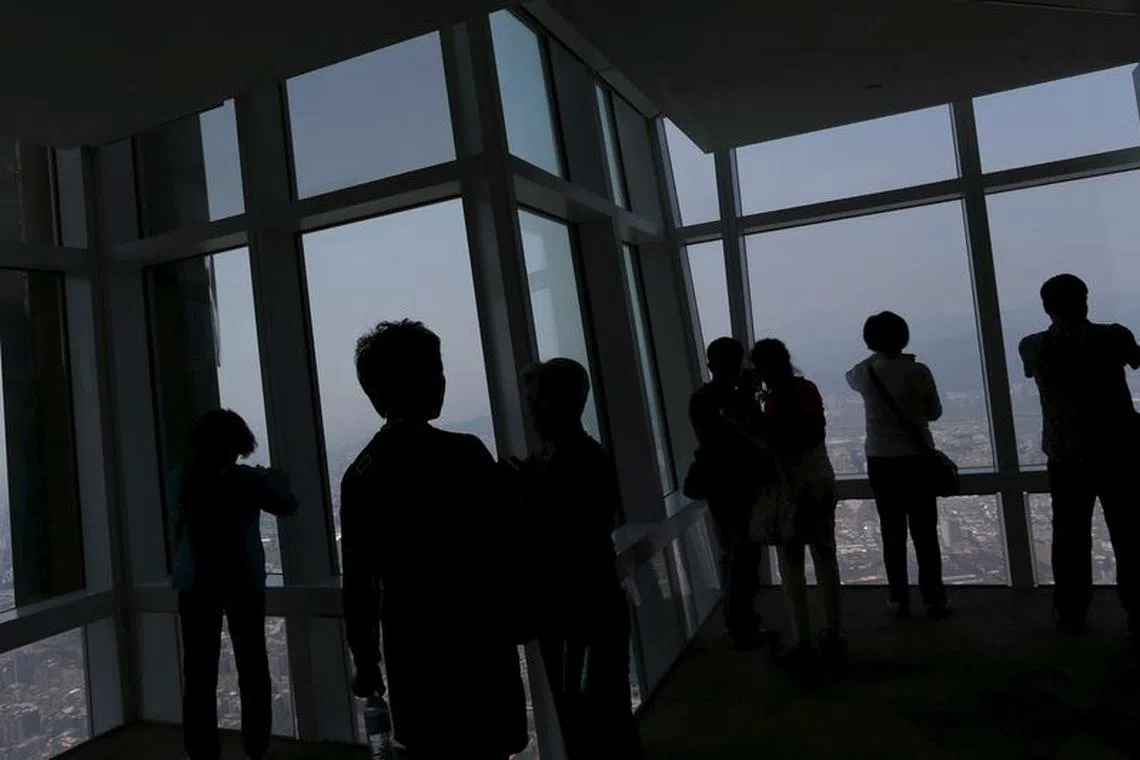 Tourists take photos of the city skyline from the Taipei 101 skyscraper building in Taipei, Taiwan March 29, 2016. REUTERS/Tyrone Siu/file photo