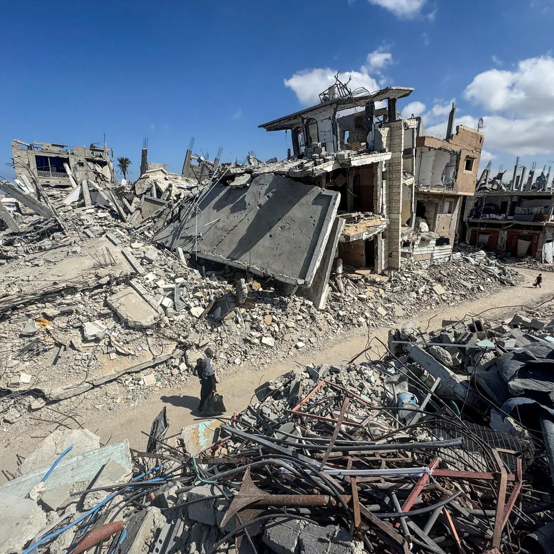 FILE PHOTO: Palestinians walk near rubble and destroyed buildings, amid the Israel-Hamas conflict, in Khan Younis, in the southern Gaza Strip, October 10, 2024. REUTERS/Mohammed Salem/File Photo