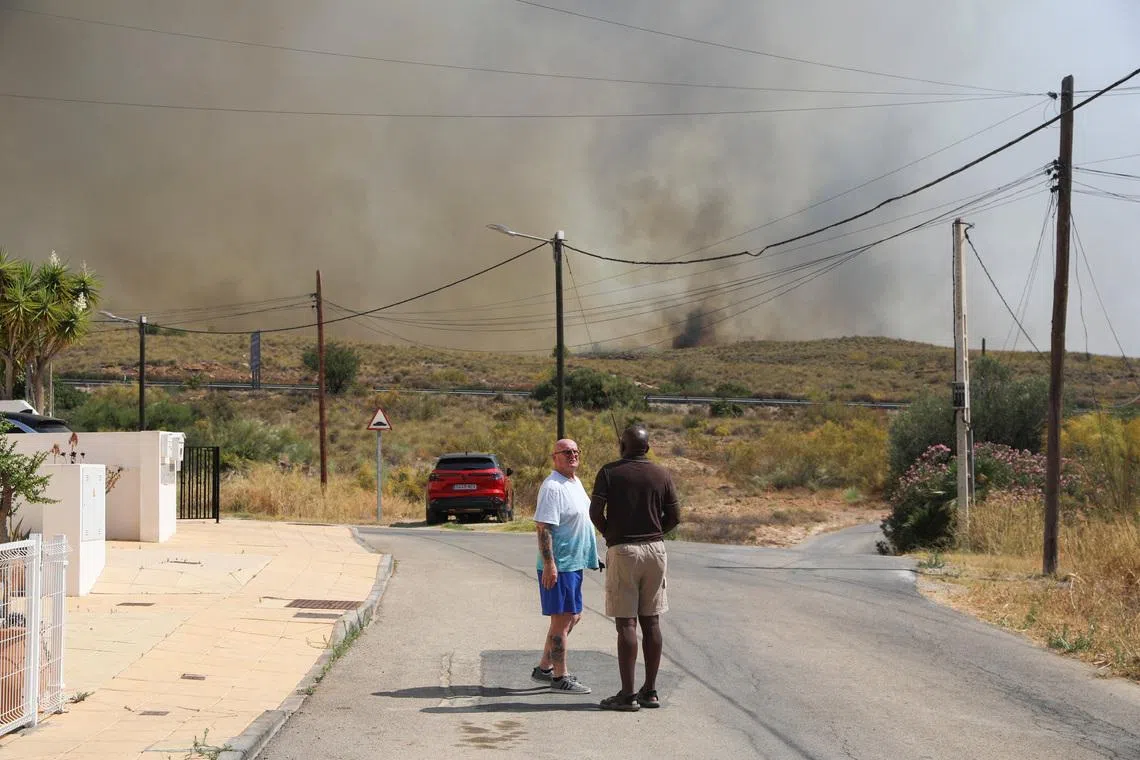 Residents get ready to leave their homes while smoke and flames rise during a wildfire in Los Gallardos, Almeria, Spain, on July 10.