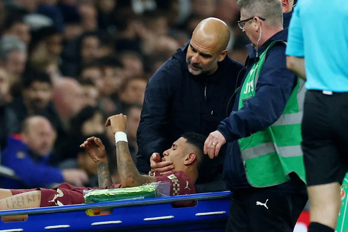 Manchester City's Savinho is carried away in a stretcher after suffering an injury in their League Cup match against Tottenham Hotspur, as Manchester City manager Pep Guardiola looks on 
