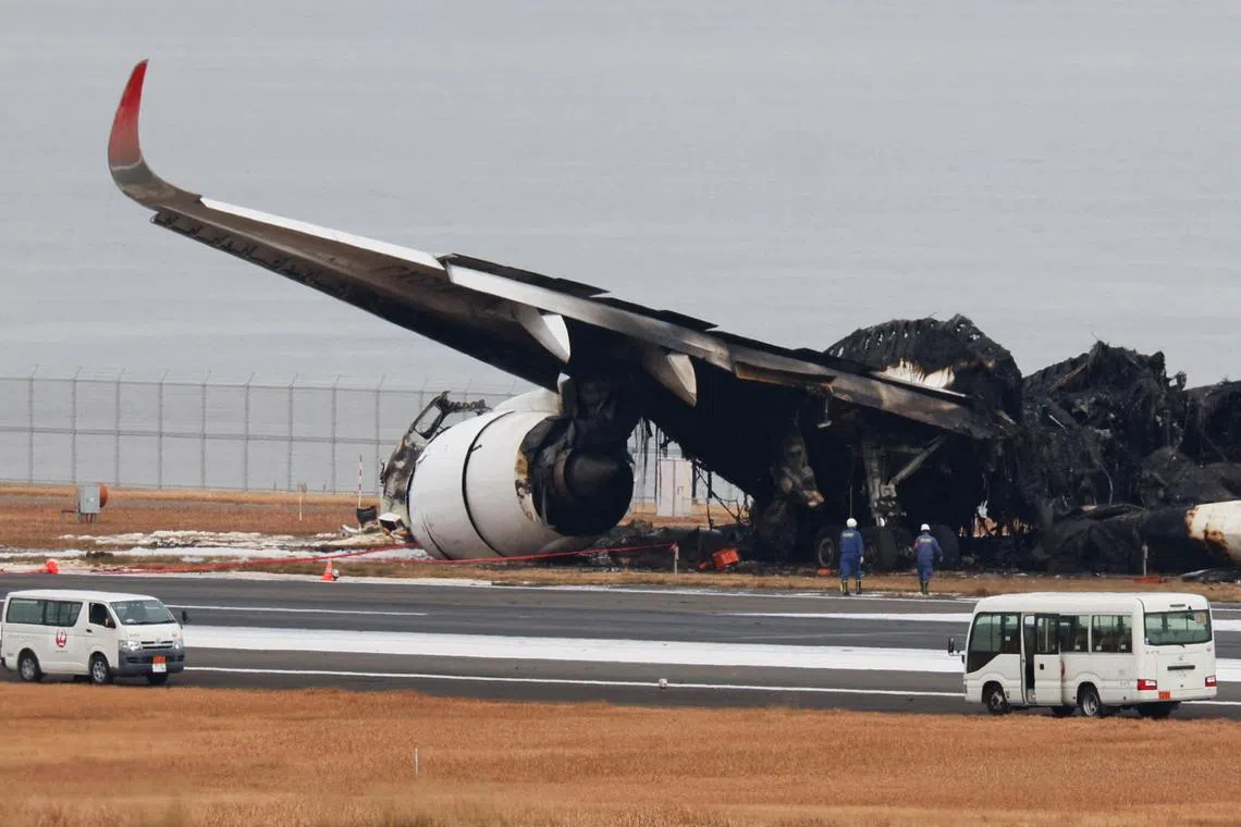Officials investigate a burnt Japan Airlines (JAL) plane after a collision with a Japan Coast Guard aircraft in Tokyo.