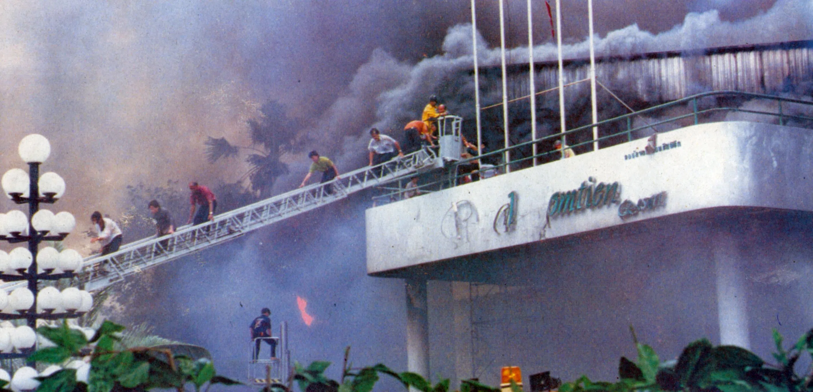 Survivors climb down a fire escape ladder from the Royal Jomtien Resort Hotel’s entrance canopy.