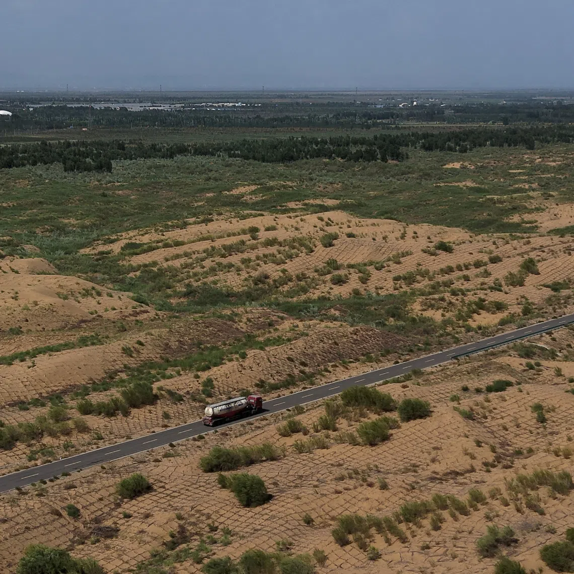 FILE PHOTO: A drone view shows a truck driving along a road at an antidesertification site, with square grids of branches sticked into the ground to prevent sand movement, in Kubuqi desert during an organized media tour, in Ordos, Inner Mongolia Autonomous Region, China, June 12, 2026. REUTERS/Maxim Shemetov/File Photo