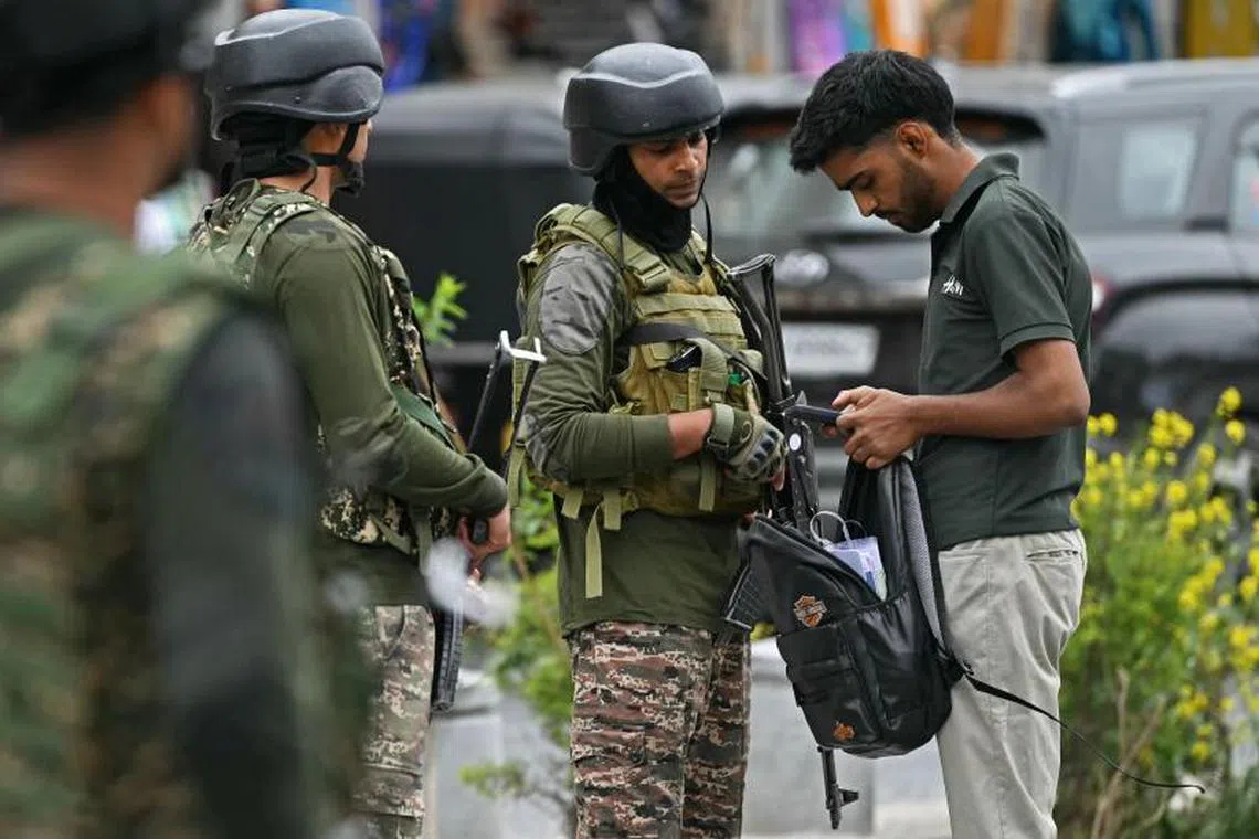 Indian paramilitary soldiers check the bag of a Kashmiri man at a marketplace in Srinagar on May 9, 2025. India said on May 9 it had repulsed a wave of Pakistani drone and artillery attacks overnight, and Islamabad insisted it had not struck targets across the border, as the latest conflict between the nuclear-armed neighbours showed no signs of relenting. (Photo by Sajjad HUSSAIN / AFP)