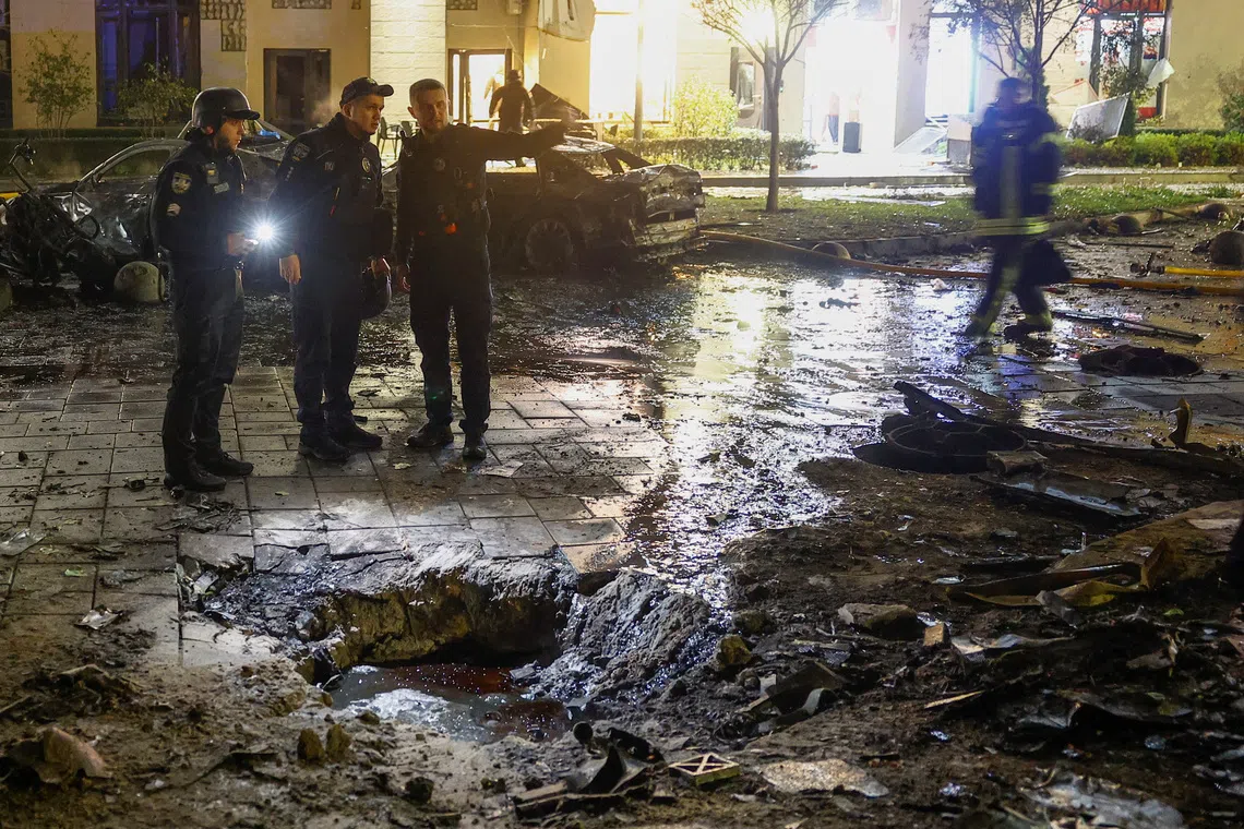 Emergency employees work at the site of a residential area damaged during a Russian drone strike in Kyiv, Ukraine, on Oct 12.