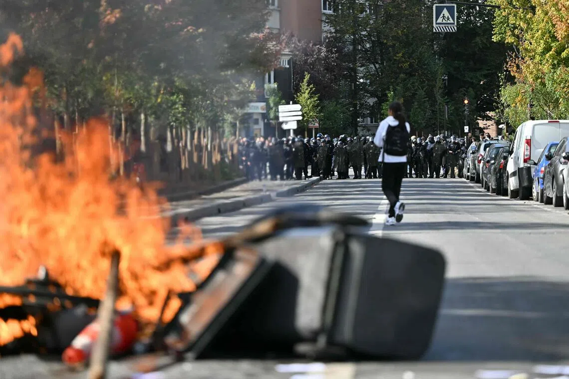 Riot police standing at a distance from a fire involving rubbish bins in Aubervilliers, north of Paris, on Oct 1, as students stage a blockade outside Le Corbusier secondary school. French officials held a crisis meeting on Oct 1 over student protests that are growing increasingly violent.