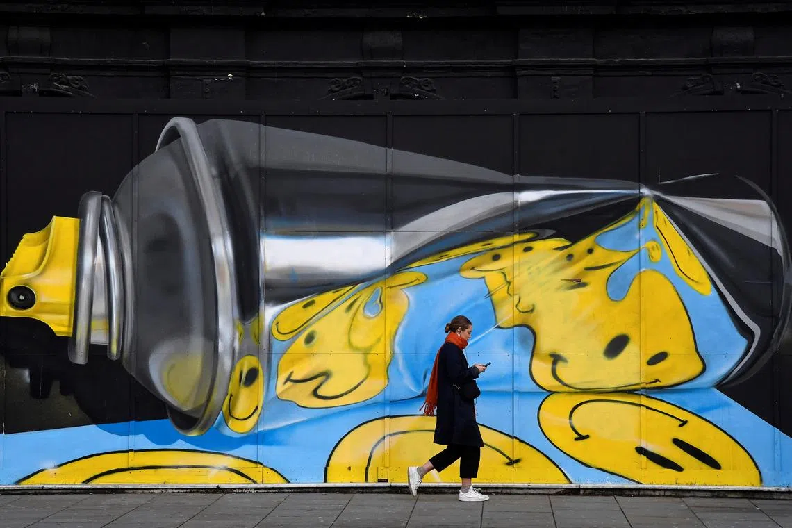 A woman views her phone as she walks past street art on a wall in London, Britain, December 18, 2019. REUTERS/Toby Melville