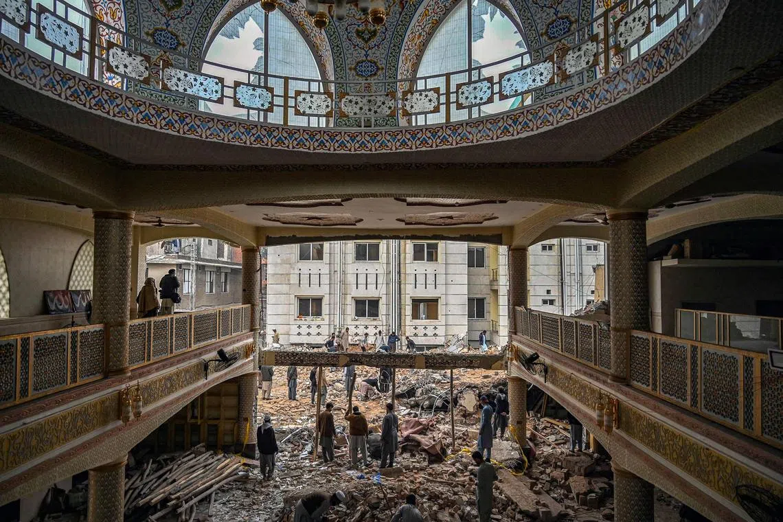 Plain-clothed policemen gather over the rubble of a damaged mosque in Peshawar on Feb 1, 2023.