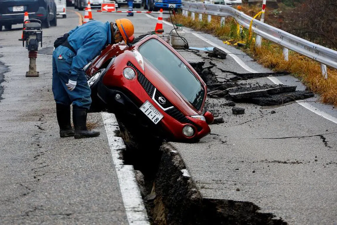 FILE PHOTO: A worker looks at a car stuck on a broken road in the aftermath of an earthquake, near Anamizu, Japan, January 3, 2024. REUTERS/Kim Kyung-Hoon/File Photo