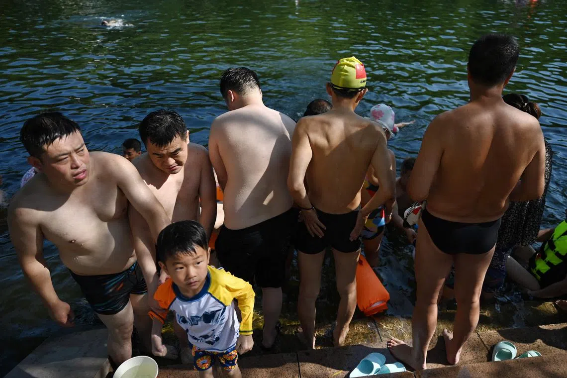 People cool off in a canal in Beijing as China's capital sweltered in temperatures around 40 deg C.