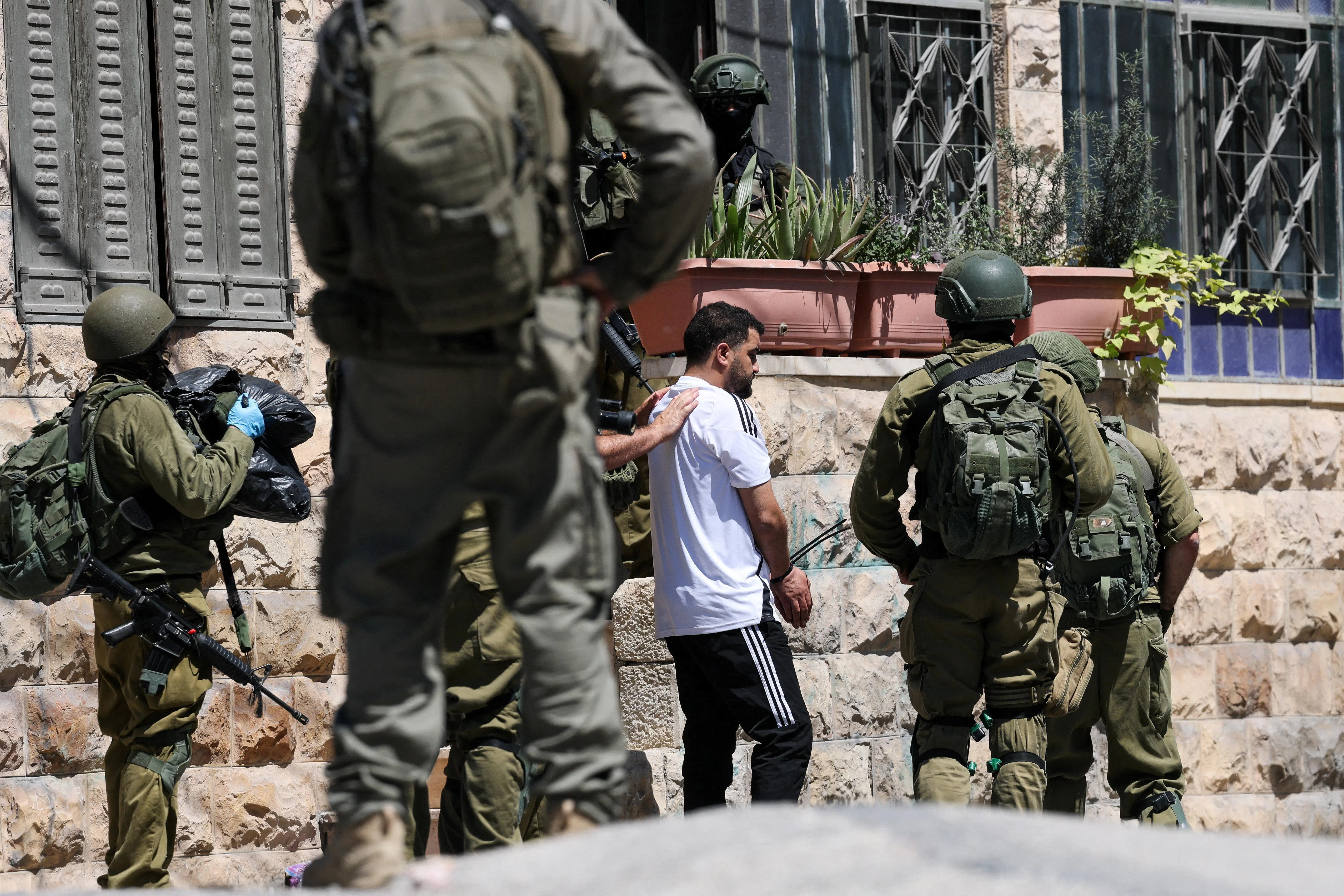 Israeli soldiers talk to a Palestinian man, as they conduct raid in Anata, in the Israeli-occupied West Bank, September 8, 2026. REUTERS/Ammar Awad     TPX IMAGES OF THE DAY