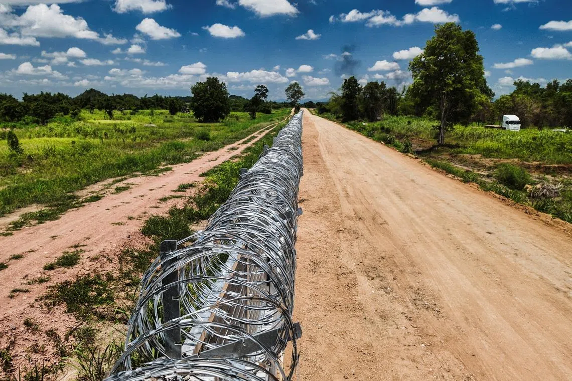 A section of the border fence between Thailand and Cambodia in Pong Nam Ron district, Chanthaburi province, where a reinforced concrete barrier topped with mesh panels and concertina razor wire was built by the Development Military Command under the Royal Thai Armed Forces Headquarters, in Thailand, July 22, 2026. REUTERS/Chalinee Thirasupa
