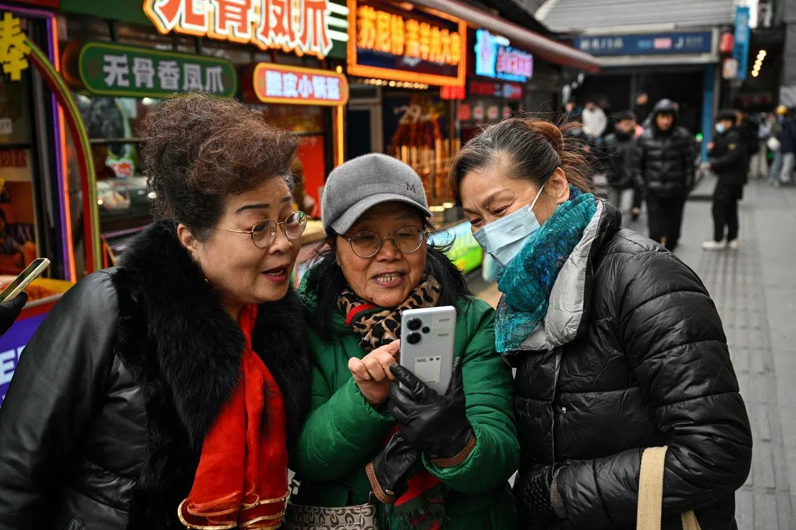 Women looking at a smartphone on a street in Wuhan - the city where Covid-19 was first detected - ahead of the fifth anniversary of China confirming its first death from the coronavirus.