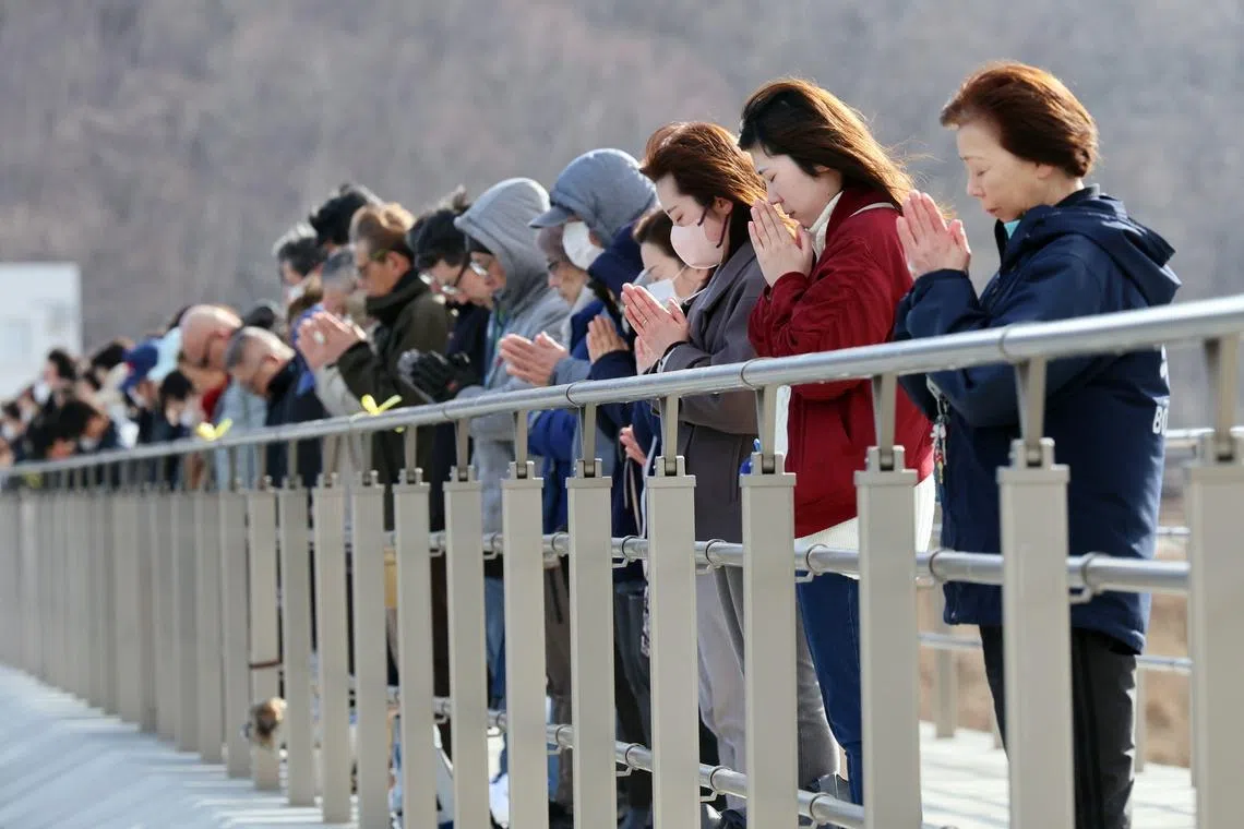 People observing a minute of silence as they pray for the victims of the earthquake in the Taro district of Miyako, Iwate Prefecture, northeastern Japan, on March 11, marking the 15th anniversary of the Great East Japan Earthquake. 