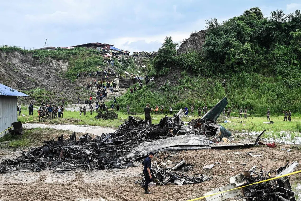 Rescuers and officials stand at the crash site after a Saurya Airlines' plane crashed during takeoff on July 24, 2024.  